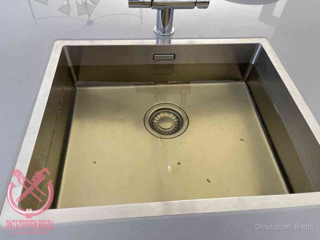 Stilstaand water in een rvs spoelbak dat niet wegloopt, een duidelijk signaal van een gootsteenverstopping in Breda