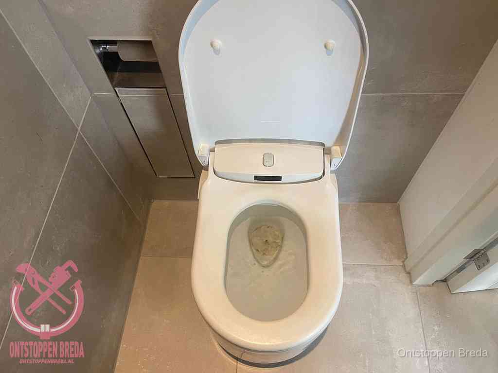 Een wit hangtoilet waarin een prop wc-papier op het water blijft drijven, een duidelijk signaal van een verstopte wc in Breda