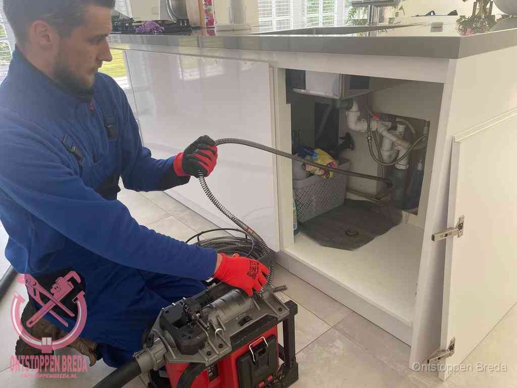 Een monteur reinigt de keukenafvoer grondig met een veermachine om terugkerende gootsteenverstoppingen te voorkomen in Breda Een monteur reinigt de keukenafvoer grondig met een veermachine om terugkerende gootsteenverstoppingen te voorkomen in Breda