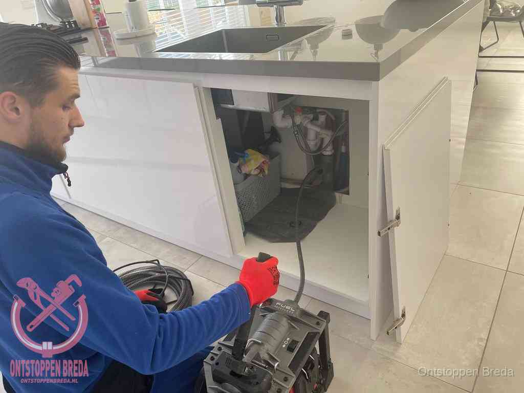 Monteur ontstopt met een veermachine een verstopte afvoer onder de gootsteen in Breda Monteur ontstopt met een veermachine een verstopte afvoer onder de gootsteen in Breda