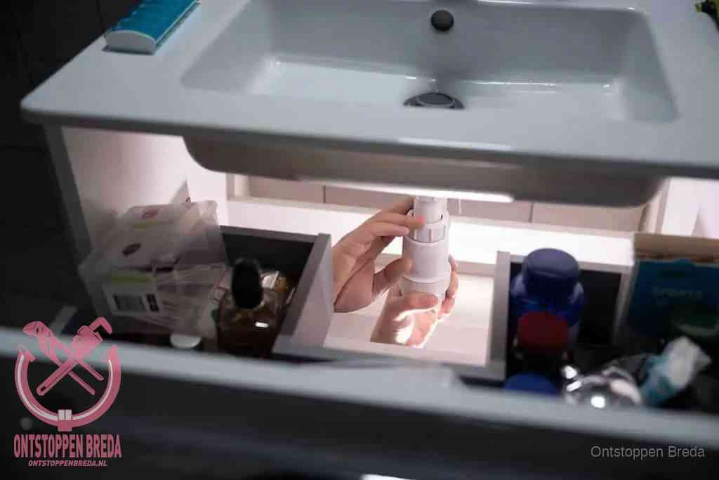 Een pompfles met zeep boven een wastafel in de toiletruimte, de warm water en afwasmiddel-methode om de wc te ontstoppen in Breda