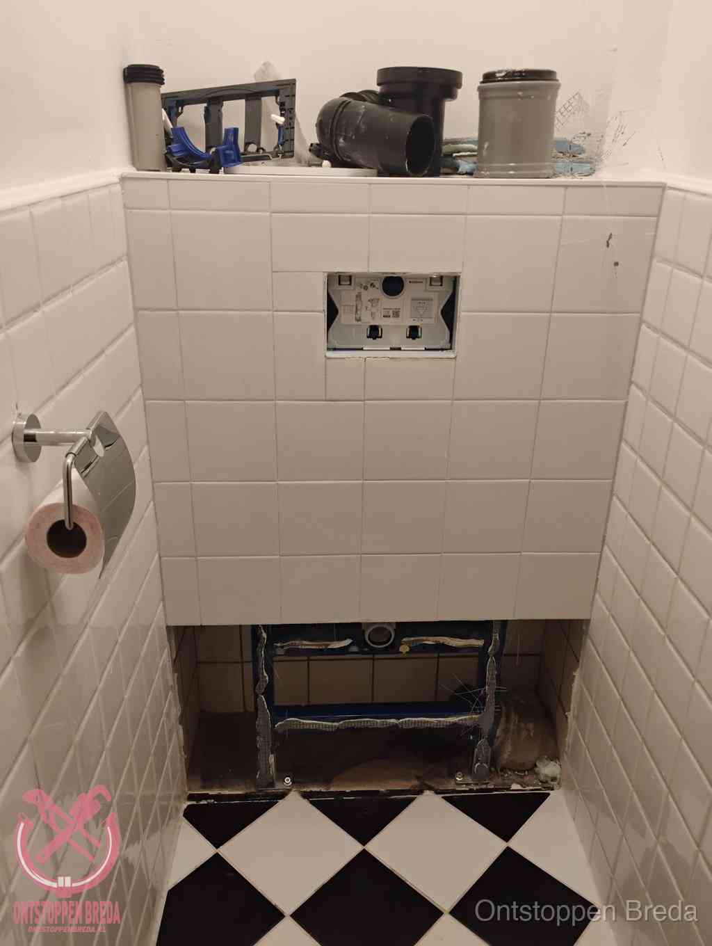 Een toiletruimte waar het hangtoilet en de inbouwreservoir-onderdelen zijn vrijgelegd voor onderhoud, periodiek nazicht voorkomt een wc-verstopping in Breda