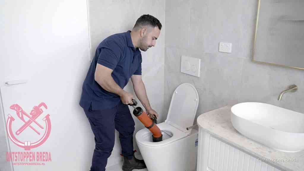 Een monteur gebruikt een handmatige perspomp (toiletontstopper) op een wandcloset tijdens het professioneel wc ontstoppen in Breda