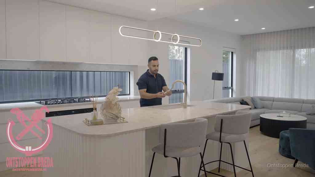 Een bewoner bij de keukenspoelbak die zelf aan de slag gaat met een verstopte gootsteen in Breda Een bewoner bij de keukenspoelbak die zelf aan de slag gaat met een verstopte gootsteen in Breda